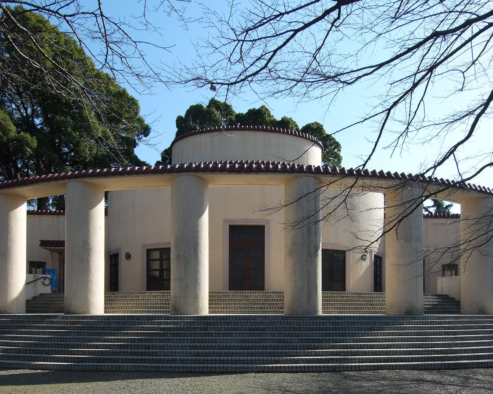 The round, colonnaded Former Tama Seiseki Memorial Hall in Sakuragaoka Park under bare winter branches