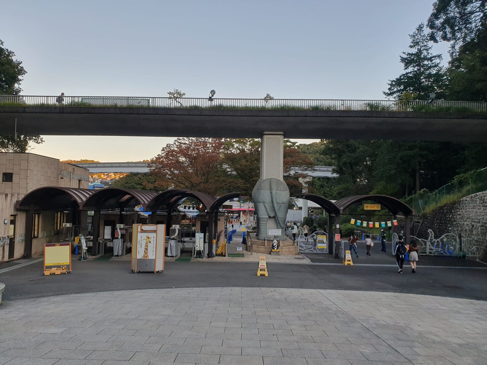 The Tama Zoo main gate with its elephant statue and ticket booths beneath a footbridge