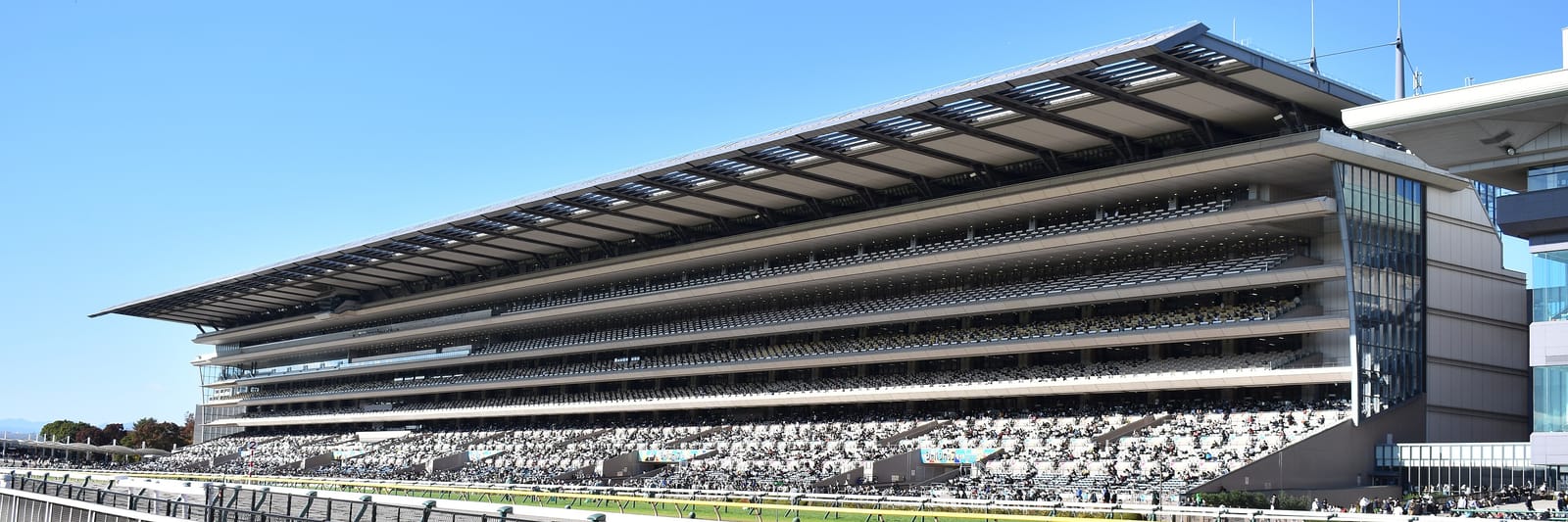 A panoramic view of the full Fuji View Stand at Tokyo Racecourse, filled with spectators.