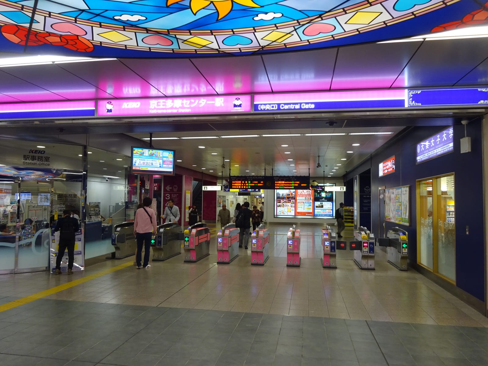 The Central Gate ticket barriers of Keio Tama Center Station under a colorful stained-glass ceiling