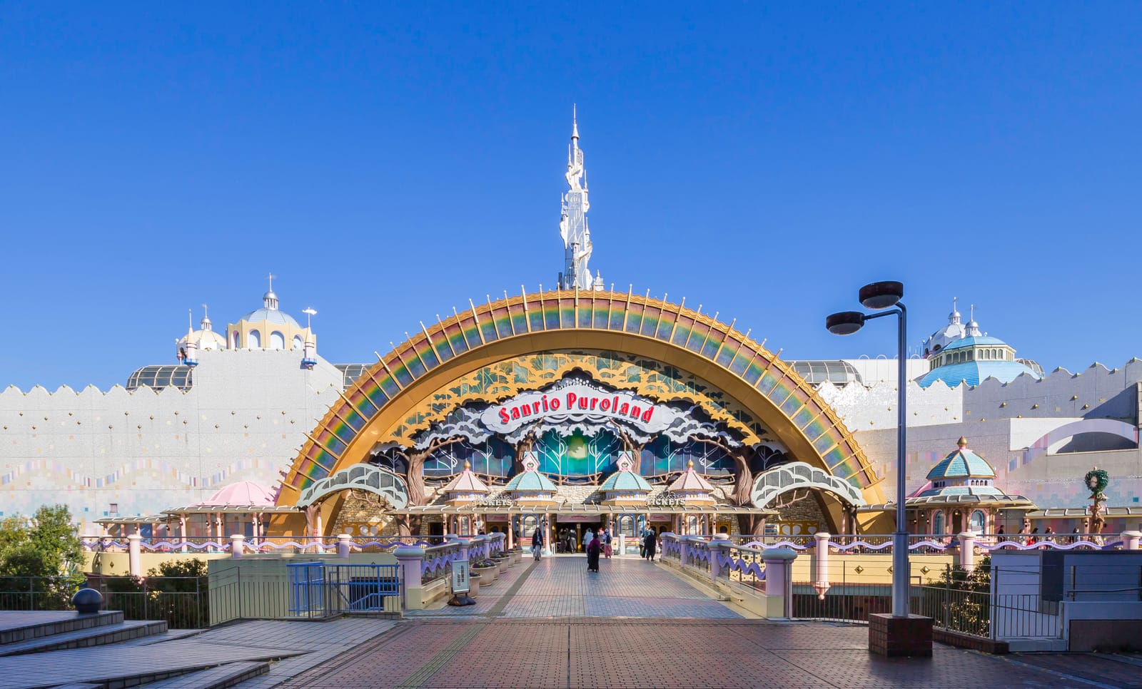 Sanrio Puroland's grand arched entrance facade, seen straight on from the approach walkway