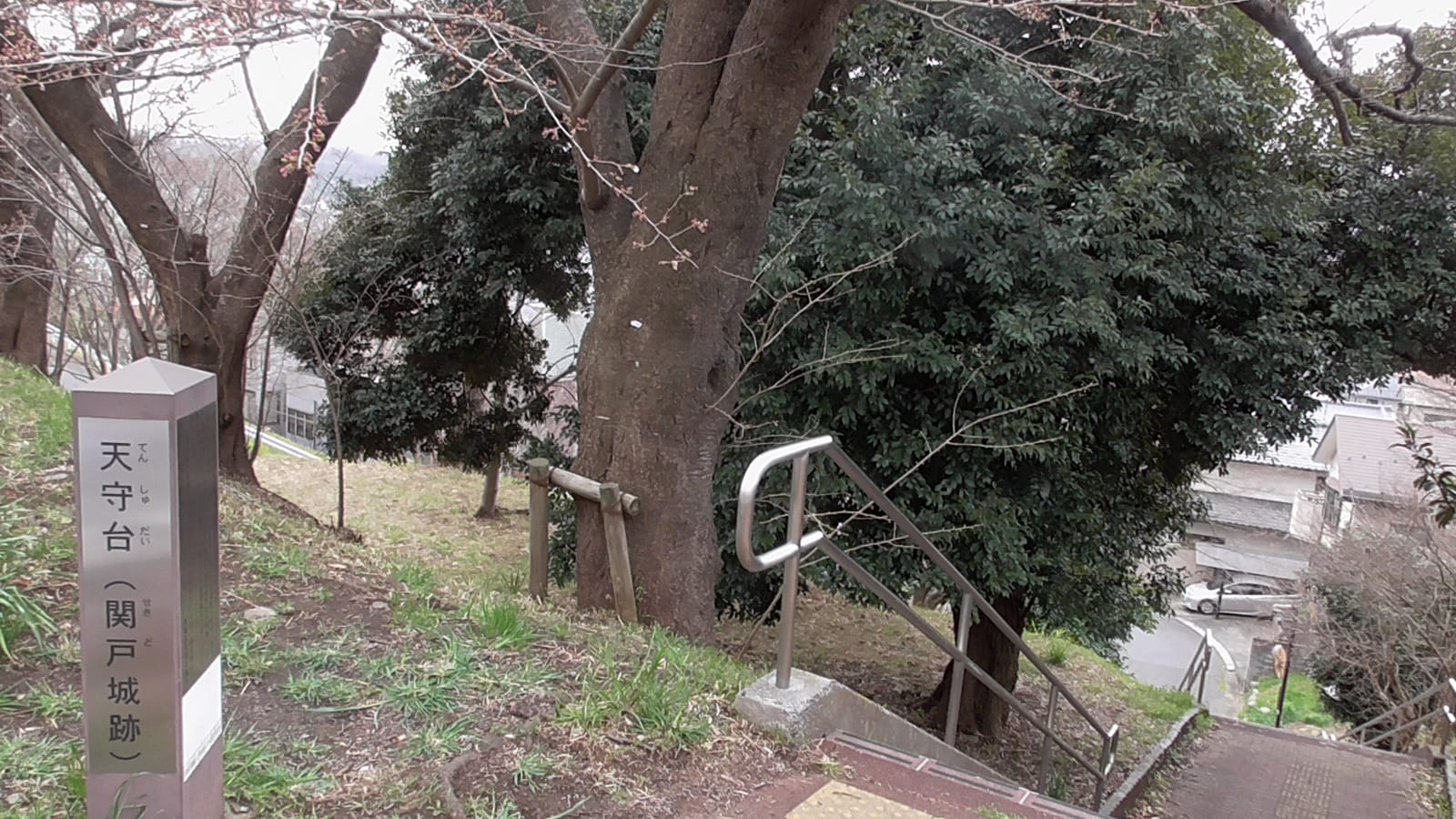 The Tenshudai (Sekido Castle site) marker post on a wooded hilltop above Sakuragaoka's houses
